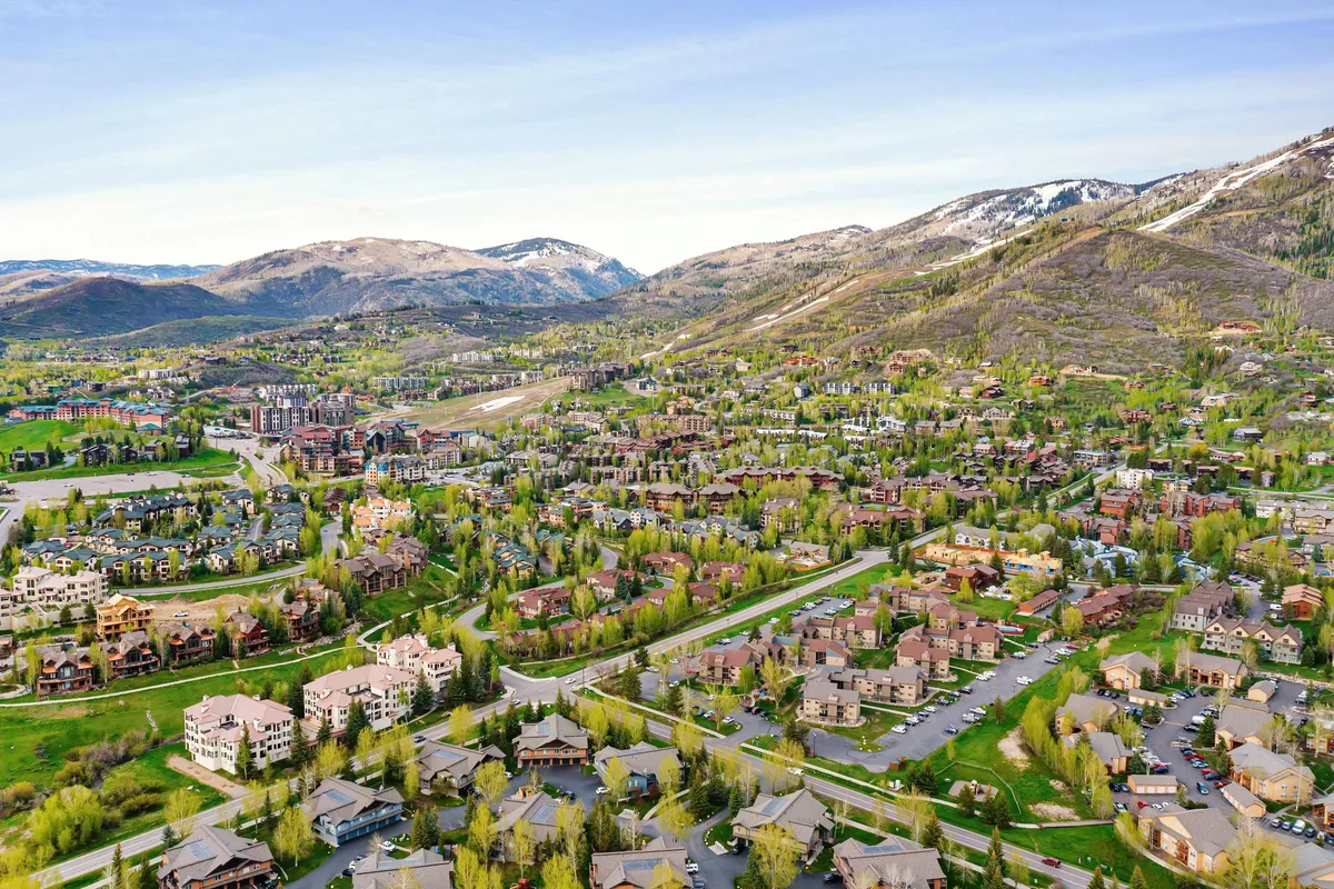 This image captures an expansive view of lush greenery with a dramatic mountain backdrop. Winding roads weave through residential areas, evoking a sense of adventure and exploration. The inviting landscape is ideal for hiking, cycling, and family outings, aligning with Steamboat's summer appeal.