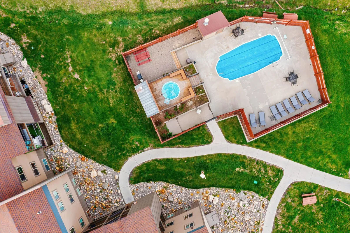 This image showcases an inviting outdoor swimming pool and hot tub area framed by pathways and lounge chairs. Both amenities are visible, with the pool perfect for sunny days and the hot tub offering a relaxing spot year-round. The scene suggests a communal, relaxed atmosphere ideal for socializing or unwinding after outdoor activities.