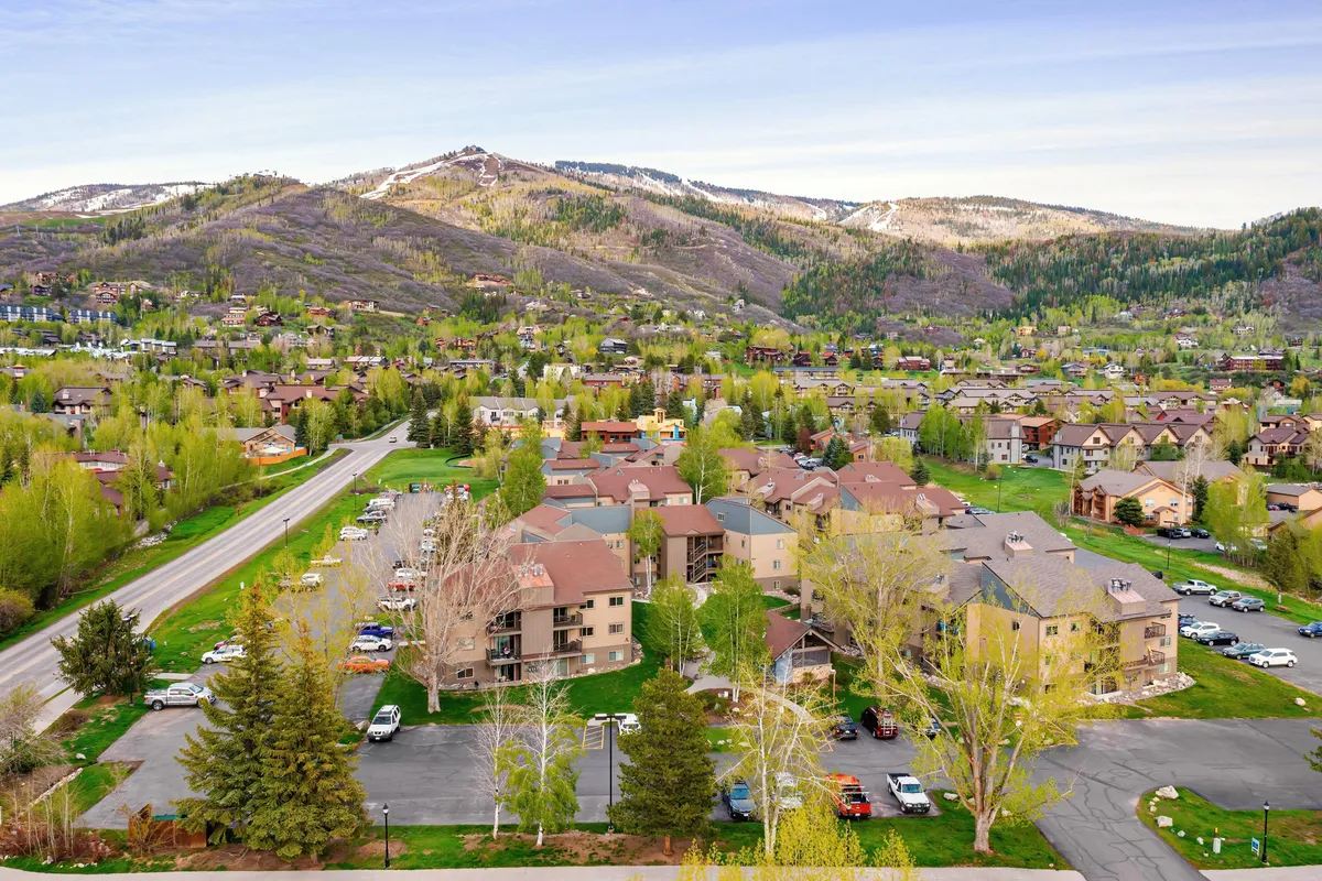A wide exterior shot shows lush greenery with a mountain backdrop, neatly arranged buildings, and clear roadways. The scene conveys easy access to the outdoors and a peaceful, community-oriented setting—perfect for those seeking adventure and relaxation after a day on the slopes.