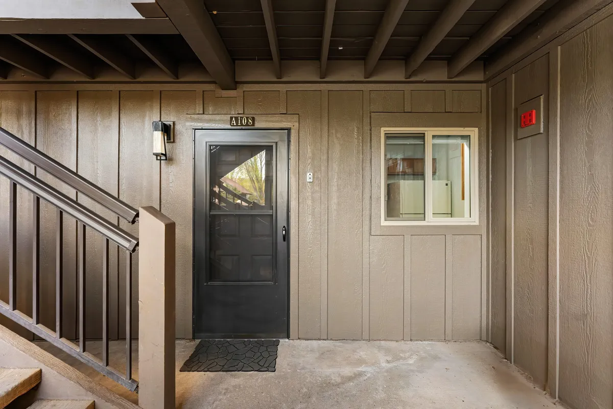 This image captures the front door, a window letting in natural light, and a staircase, conveying a sense of entry and transition from the outside world. The inviting mood suggests the excitement of arriving at or returning from local adventures.