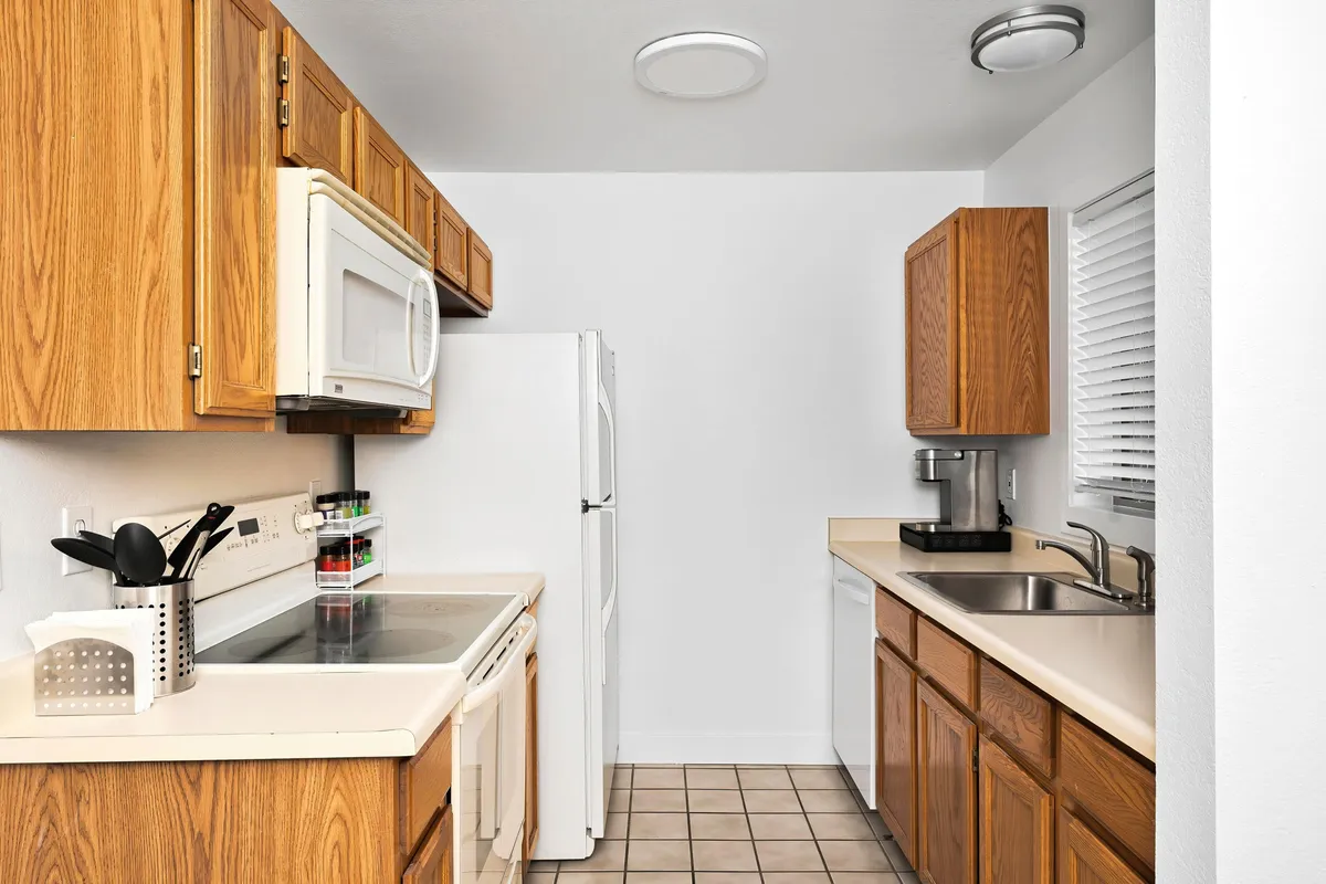 A close-up view of the kitchen, focusing on cabinetry, modern appliances, and the sink area. The space is organized, practical, and inviting, suggesting a well-equipped setting for cooking and family gatherings.